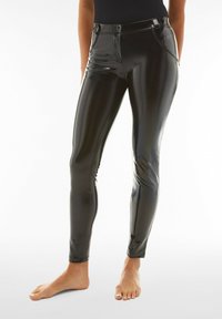 Mustat, korkeavyötäröiset tekonahkaleggingsit kiiltävällä pinnalla, joissa on vetoketjusulku, etutaskut ja kapea malli, joka kapenee nilkoissa.