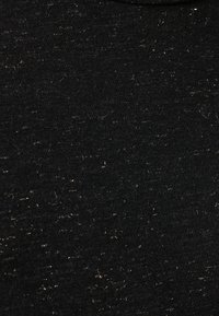 Superficie de tela negra cubierta de numerosas pequeñas partículas de pelusa blanca esparcidas de manera desigual.