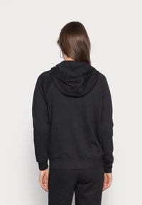 Svart hoodie tillverkad av mjukt tyg. Har en känguruficka och ribbade muddar. Enkel, odekorerad design.