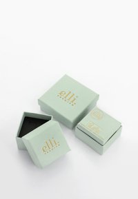 Myntegrønne papkasser med guldfolie branding; en firkantet kasse og en sekskantet kasse, begge med sorte indvendige og minimalistisk design.
