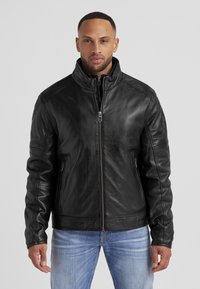 Schwarze Lederjacke mit hohem Kragen und einem Frontreißverschluss, ausgestattet mit Seitentaschen und genähten Details an den Ärmeln.