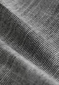 Texturovaná tkanina v černobílém vzoru houndstooth, která má tkaný design s jemnými detaily a jemným leskem. Měkký povrch.