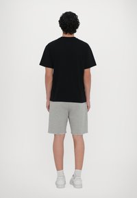 T-shirt negru din bumbac cu mâneci scurte, asortat cu pantaloni scurți gri din bumbac. Ținuta este completată cu adidași albi.