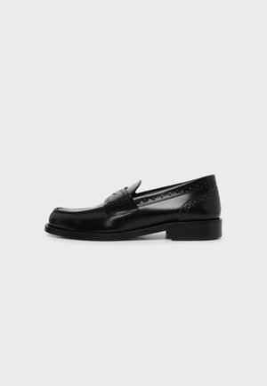 Black leather loafer with decorative perforations and a low heel, shown from the side on a plain light background.