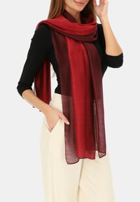 Szalik o bordo gradientowym kolorze wykonany z lekkiej, teksturowanej tkaniny, elegancko układający się wokół szyi i ramion, dodający miękki akcent do stroju.