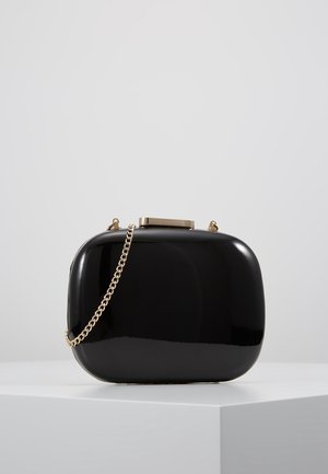 Czarna kopertówka z lakierowanej skóry o smukłym, prostokątnym kształcie. Posiada złoty łańcuszkowy pasek i metaliczne zapięcie na górze.