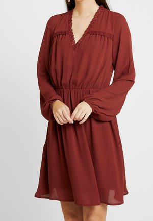 Robe bordeaux à manches longues, décolleté en V et détails en dentelle le long du décolleté et du corsage ; taille élastique pour un effet froncé.