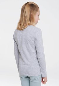 Langärmliges graues T-Shirt aus Baumwolle, mit einem schlichten Design und rundem Ausschnitt, von hinten gesehen. Kombiniert mit hellen Hosen.