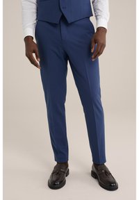 Niebieskie spodnie w jednolitym kroju o slim fit, uszyte z gładkiego materiału, z płaskim przodem i kieszeniami bocznymi, zestawione z brązowymi mokasynami.