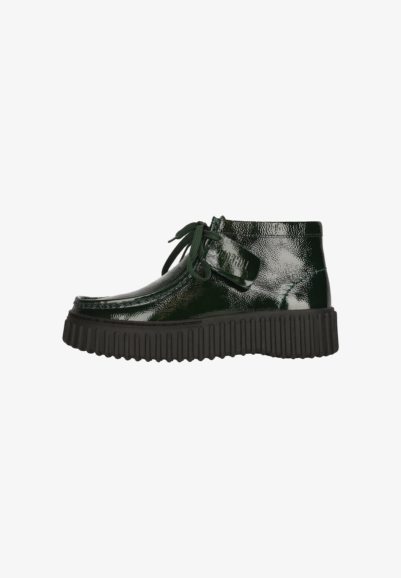 Bottines en cuir verni vert avec une semelle en caoutchouc noir épaisse, bout rond et lacets assortis. Détail de boucle sur le côté pour un ajustement sécurisé.