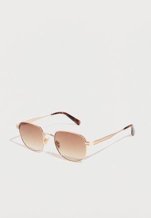 Γυαλιά ηλίου με χρυσή μπροστινή όψη, καφέ φακούς με βαθμιαία μετάβαση και άκρες στα βραχίονες σε σχέδιο κελύφους χελώνας σε λευκό φόντο.