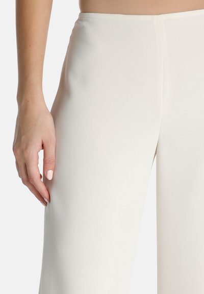 Pantalons larges en tissu léger et lisse de couleur crème. Présentent une taille ajustée avec une simple couture sur le côté.