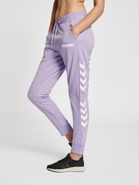 Lavendel joggerbukser lavet af blødt materiale med drawstring talje, sidelommer og hvidt chevron mønster langs de ydre ben.