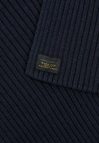 Tissu en tricot côtelé marine avec une texture douce ; comporte une étiquette indiquant "camel active Fabriqué pour les aventures quotidiennes" en noir et or.