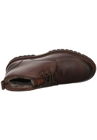 Bottine en cuir marron avec lacets, doublure en fausse fourrure, bout rond et semelle en caoutchouc. Présente des coutures discrètes et une languette au talon.