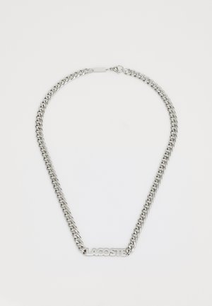 Collier en chaîne en argent avec des maillons entrelacés et un logo "LACOSTE" central. Texture lisse avec une finition polie. Fermeture par un fermoir.