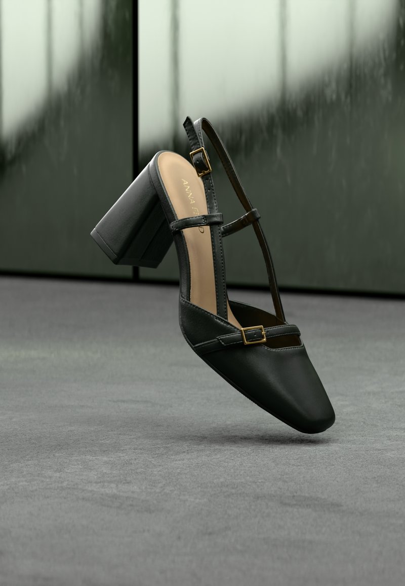 Chaussure à talon haut en cuir noir avec un bout pointu, des brides à la cheville et des accents en métal doré. Texture lisse et design de talon bloc solide.