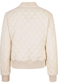 Chaqueta ligera acolchada en un suave color beige, con puños y dobladillo acanalados, que presenta un alto cuello y un patrón de diamantes en la tela.