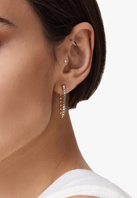 Gli orecchini a cerchio in oro e argento presentano perline rotonde alternate e un design a barra elegante, evidenziando diverse trame e finiture.