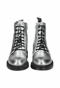 Bottines argentées avec une finition brillante, des lacets noirs, une fermeture éclair sur le côté et une semelle texturée pour l'adhérence.