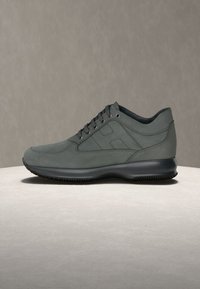 Green leather sneaker with tonal stitching, eight eyelets, and a rubber sole. Rounded toe and textured side panel detail.