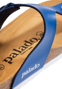 Blå tongsandaler med en matt läderrem, korkfotbädd och vit gummisula. "Palado"-logotyp tryckt på fotbädden.