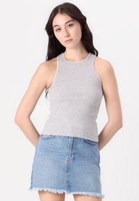Gray ribbed tank top with a high neckline and contrasting white stitching, paired with a light blue denim skirt featuring frayed hem.
