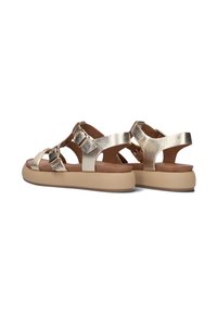 Sandali metallici dorati con cinturini incrociati, fibbie e una suola in beige. Presentano una texture liscia e un design con tallone aperto.