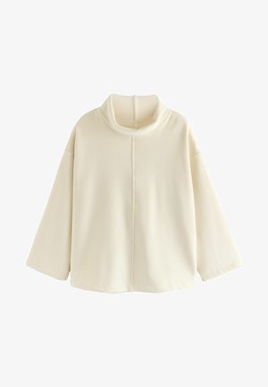 Pull en crème surdimensionné avec un col haut, texture côtelée et épaules tombantes, comportant une couture centrale sur le devant.