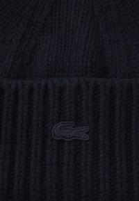 Beanie nero a maglia realizzato in lana, caratterizzato da una texture a costine e un piccolo logo ricamato nero sul davanti.