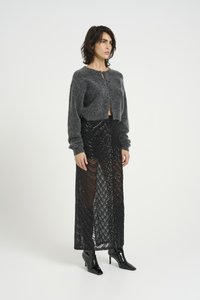 Gray cropped cardigan with a front closure paired with a black sequin maxi skirt featuring a wave pattern and accentuated with glossy black boots.