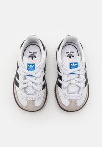 Sneakers bianche con strisce nere e dettagli grigi. Realizzate in pelle, con suola testurizzata, design con lacci e dettaglio logo blu.