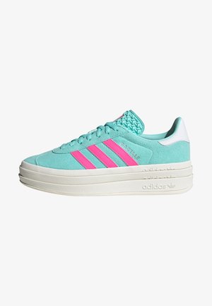 Zapatilla Adidas Gazelle turquesa con tres rayas rosas, lengüeta trasera blanca, parte superior de ante y suela gruesa de goma blanca.
