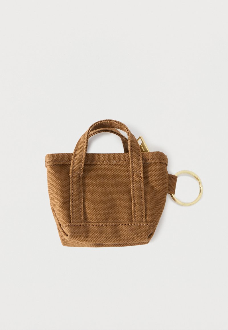 Portachiavi a borsa tote piccola in tela marrone con doppi manici e un anello di metallo dorato attaccato su sfondo bianco.