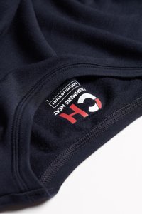 Námořnický tkaninový oděv s hladkým povrchem, na kterém se nachází štítek s logem v bílé, červené a černé barvě. Stehy viditelné podél okrajů.