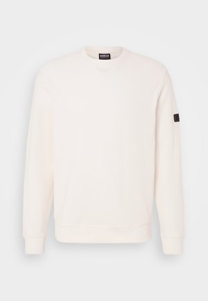 Hele kreemja värviga pehme puuvillaseguse sviitriga, millel on ümmargune kaelus, pikad varrukad, ribakujulised varrukasuud ja väike logopatch vasakul varrukal.