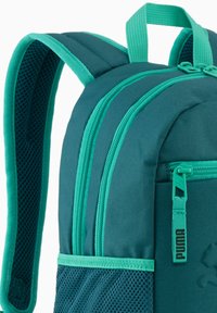 Sac à dos turquoise avec bretelles en mesh rembourrées, compartiments zippés et une poche latérale en mesh. Présente un logo et des coutures contrastantes.