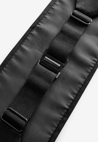 Correa de tela negra con una textura suave, que cuenta con dos hebillas negras ajustables y un diseño elegante y plano.
