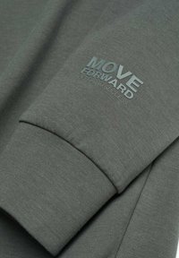 Manche vert foncé avec la phrase « AVANCEZ SUR LA ROUTE DU SUCCÈS » imprimée en lettres vertes assorties.