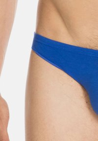 Blauer Baumwoll-Tanga mit glatter Textur, niedrig geschnitten und minimaler Abdeckung. Der Bund ist verstärkt für mehr Haltbarkeit.