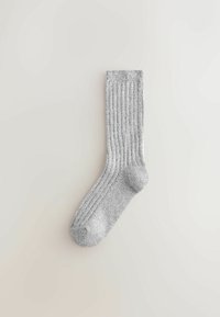 Szara skarpetka w prążki o miękkiej teksturze, o długości do połowy łydki, z wzmocnionymi piętą i palcami, wyeksponowana na jasnym tle.