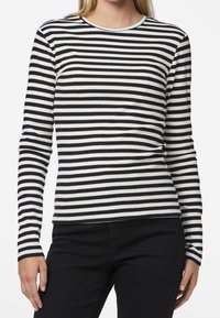 Långärmad ribbad topp med svart och vit horisontell randning, rund halsringning och figurnära silhuett.