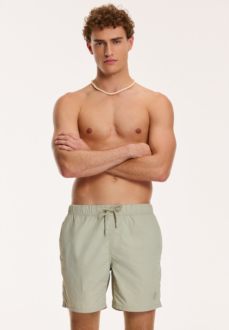 Light green swim shorts made of lightweight fabric, featuring an elastic waistband and drawstring. Simple design with no prominent patterns.
