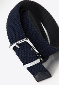 Cinturón tejido en color navy con hebilla de metal plateado y un acento de cuero, que presenta un patrón texturizado en toda la correa.