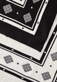 Sciarpa a motivi bianco e nero con quadrati, rettangoli e punti geometrici, caratterizzata da una texture liscia e un design sovrapposto.
