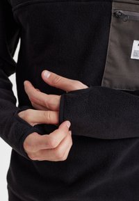 Sort fleece pullover med en lynlåslomme, der har en kontrasterende grå panel og fingerhulsmuffer for ekstra komfort.