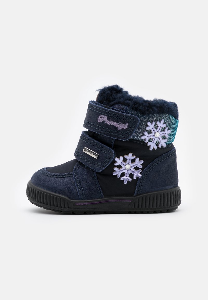 Botte d'hiver bleu marine avec deux sangles Velcro, doublure en fausse fourrure et accents de flocon de neige brodés en violet avec des détails en gemmes. Semelle en caoutchouc.
