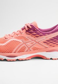 Scarpa da corsa leggera in materiale mesh corallo e viola con accenti bianchi. Presenta una tomaia testurizzata e una suola imbottita per il comfort.