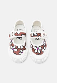 Ζεύγος παπουτσιών Mary Jane με λευκή σόλα και καφέ ύφασμα που διαθέτει λευκά και μωβ σχέδια λουλουδιών και ρυθμιζόμενες λουρίδες με αγκράφα.