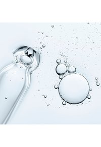 Klar glassflaske med avrundet topp og glatt kropp, omgitt av luftbobler i ulike størrelser på en lys bakgrunn.